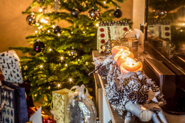four burning advent candles, beautiful decorated setup lights in Background christmas tree with gifts