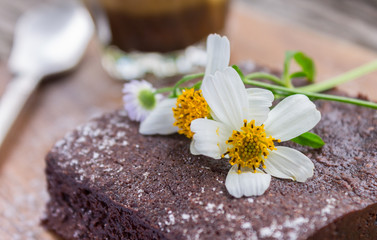 Obraz na płótnie Canvas Daisy Flower on Chocolate Brownie Cake with Latte Coffee on Wood Table Right Close Up