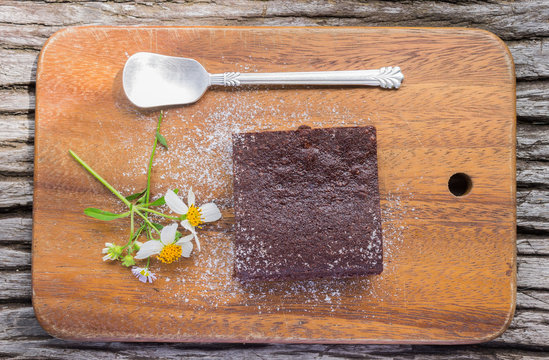 Chocolate Brownie Cake and Daisy Flower on Chopping Board on Wood Table Flatray