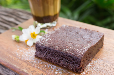 Chocolate Brownie Cake and Coffee and Daisy on Chopping Board on Wood Table