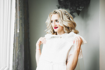 Obraz premium Luxury bride in white dress posing while preparing for the wedding ceremony