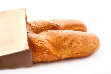 Two fresh baguettes with sesame in paper bag isolated on white background
