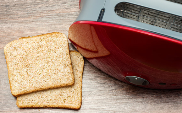 Modern toaster with toasted sliced  bread on wooden background. Kitchen equipment.Top view