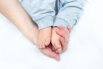 mother is holding feet of her newborn baby