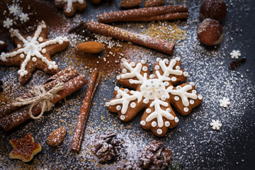 Christmas or New Year background of Gingerbread cookies, spices, nuts with sugar and snowflakes. Top view on dark stone background