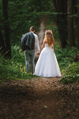 Newlyweds holding their hands during the walk in a forest