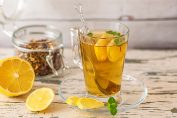 Cup of Lemon tea with lemon slices and mint on light wooden table