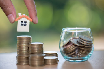 Woman hand hold a  home model put on the stack coin with growing, Savings money for buy house and...