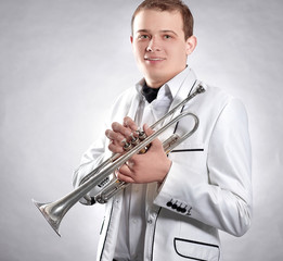 young man in a white suit with a trumpet.isolated on black background