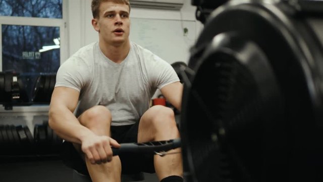Fitness young man using rowing machine in the gym crossfit training at night student professional athlete bodybuilder