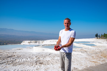 Happy traveler stands with a ripe pomegranate in his hands
