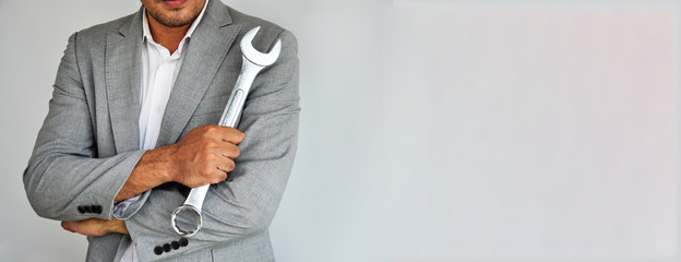 Man holding wrench on grey background with copy space.