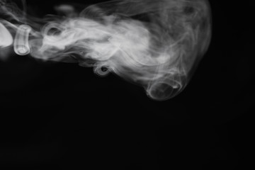 White smoke on a black background. Texture of smoke. Clubs of white smoke on a dark background for an overlay