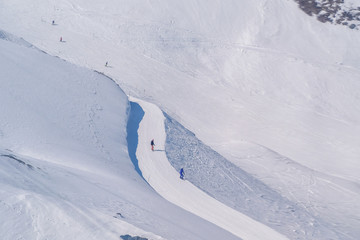 Skiers skiing down the mountain on a beautiful sunny day in Switzerland.