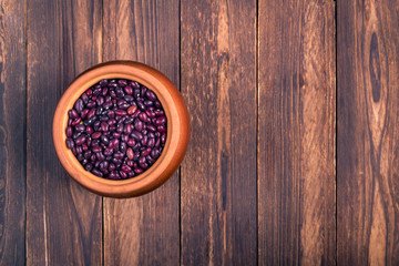 The concept of natural healthy food. Grains of brown beans in a large ceramic pot, closeup. Superfood