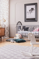 Vertical view of black and white map in frame above wooden crib with pillows, real photo with carpet on the wooden floor