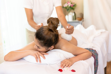 Obraz na płótnie Canvas Happy woman with masseur hand which woman with eyes closed having a massage with herbal compresses in a spa