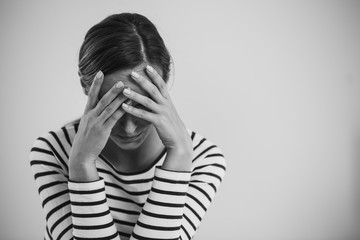 Black and white photo of young hopeless woman suffering from depression and holding her head, photo...