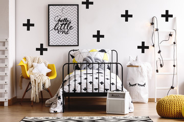 Black and grey graphic on white wall with black crosses in stylish bedroom interior for kid © Photographee.eu