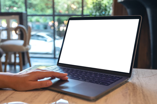Mockup image of hands using and touching on laptop touchpad with blank white desktop screen in cafe