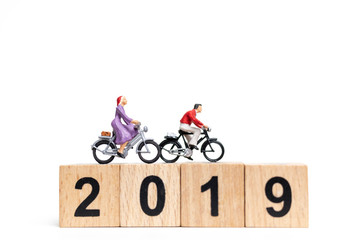 Miniature people : Friend Group ride bicycle with wooden number  2019 , Happy New Year  concept.