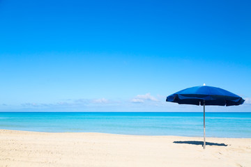 Blue beach umbrella parasol on the tropical beach. Vacation background.