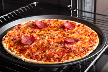 Cooking homemade pizza with salami sausage