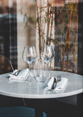 Table setting in a French restaurant. View through a window from a street.