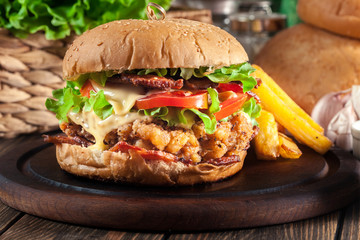 Delicious burger with chicken, bacon, tomato and cheese