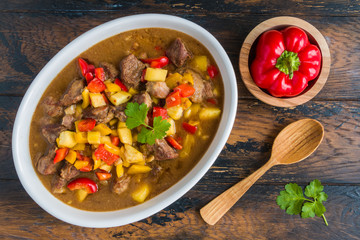 Slow cooked beef casserole. Meat and vegetables stewed in beer. Wooden rustic table, top view