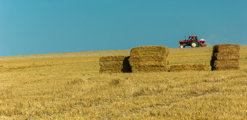 Tractors driving on the field and hay stacks