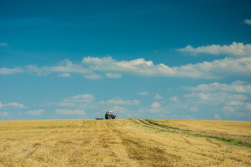 Obraz premium Tractor driving on stubble