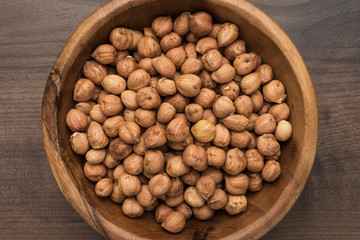 close-up photo of a bowl full of hazelnuts on the brown wooden table