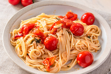 Pasta al pomodoro - spaghetti with cherry tomatoes on a plate close-up in a rustic style