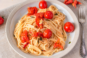 Pasta al pomodoro - spaghetti with cherry tomatoes on a plate close-up in a rustic style