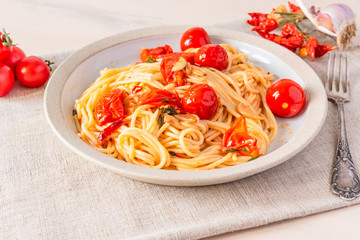Pasta al pomodoro - spaghetti with cherry tomatoes on a plate close-up in a rustic style