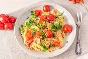 Pasta al pomodoro - spaghetti with cherry tomatoes on a plate close-up in a rustic style, top view