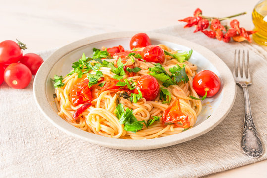Pasta al pomodoro - spaghetti with cherry tomatoes and parsley on a plate close up in a rustic style