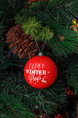 Christmas tree hanging ornament, red globe with happy winter days, close up