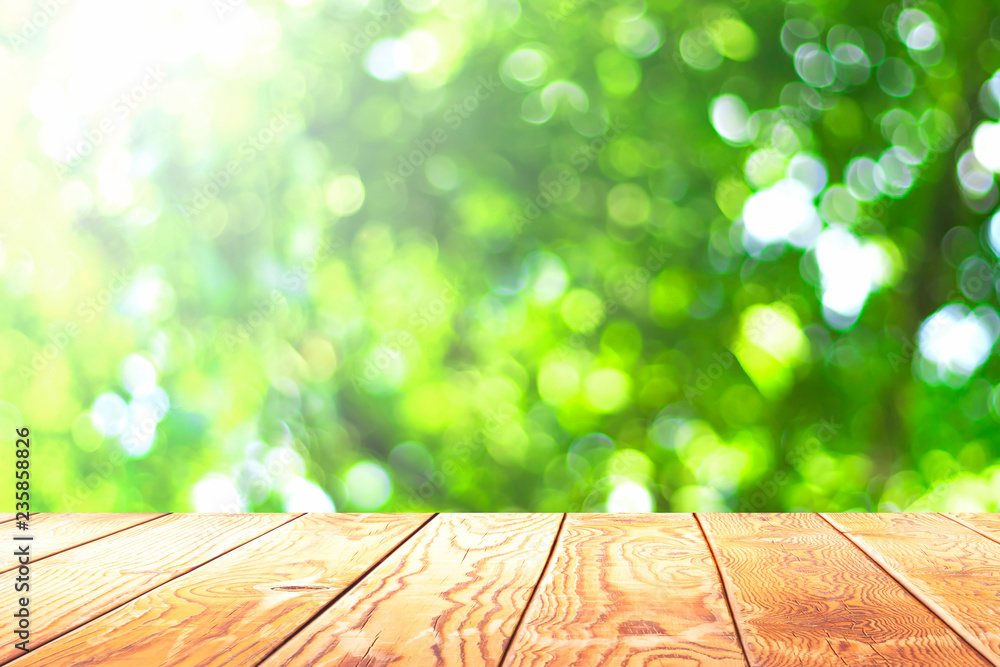 Wall mural earth day concept: empty wooden table over blurred tree with bokeh background