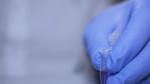 Close up of hands of scientist in gloves holding pipette and pouring solutions into test tube. GMO. DNA. Medical worker . Student used laboratory vessels in experiments. Work in the laboratory