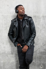 Obraz premium cool young black man in leather jacket listening to music with headphones