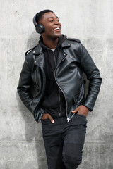 Obraz premium smiling black man in leather jacket listening to music with headphones