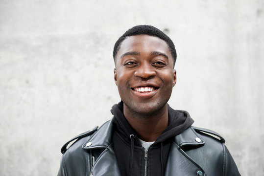 Close up portrait of happy young black man against gray wall