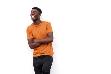 happy young black guy laughing with arms crossed against isolated white background