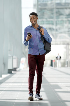 Full body young black man traveling with bag and mobile phone at station