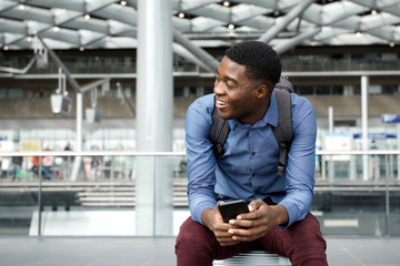 happy young travel man sitting on suitcase with mobile phone