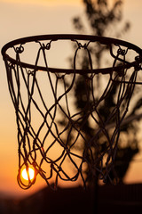 Silhouette of a basketball hoop, under the sunset