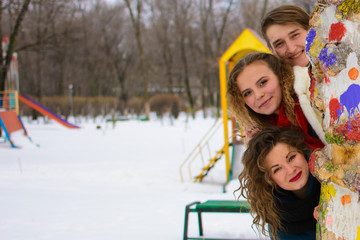 three friends are posing in winter at a tree