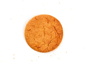 An overhead photo of a single ginger cookie on a white background with crumbs